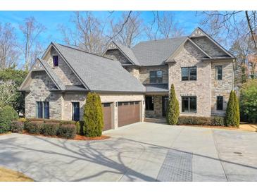 Brick house with three-car garage and manicured landscaping at 2465 Henderson Rd, Tucker, GA 30084