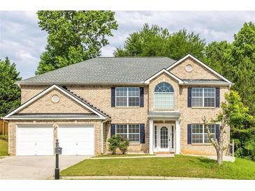 Two-story brick house with a two-car garage and landscaped lawn at 1598 Blue Spruce Ln, Conyers, GA 30012