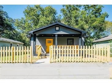 Charming gray house with yellow door, wood fence, and covered porch at 1043 Smith Sw St, Atlanta, GA 30310