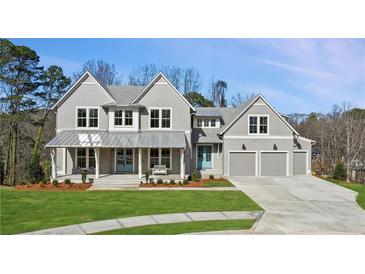 Charming two-story home with gray siding, metal roof, covered porch, manicured lawn, and attached two-car garage at 165 Grayton Ln, Roswell, GA 30075