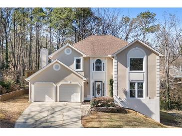 Two-story house with beige exterior, two-car garage, and landscaping at 1362 Meadow Creek Nw Way, Acworth, GA 30102