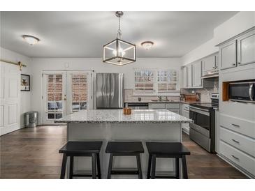 Bright kitchen features a granite island, stainless appliances, and gray cabinets at 2725 Shoreland Sw Dr, Atlanta, GA 30331
