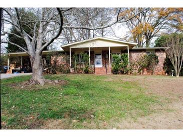 Brick ranch house with covered porch, driveway, and mature landscaping at 2499 Little John Se Trl, Marietta, GA 30067