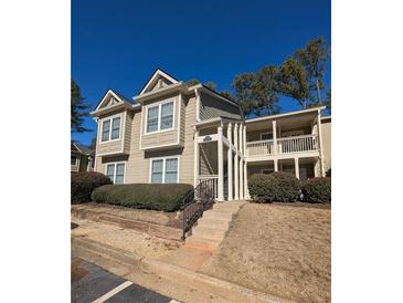 Two-story condo building with light beige siding, balconies, and landscaping at 21 Muncy Se Ct, Smyrna, GA 30080