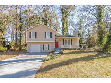 Tan house with red door, attached garage, and landscaped yard at 3794 Whaley Ct, Snellville, GA 30039