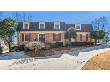 Charming brick home featuring red shutters, dormer windows, and a well-manicured front yard at 5545 Woodsong Trl, Dunwoody, GA 30338