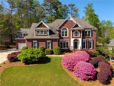Stunning brick home featuring a manicured lawn, colorful azaleas, and classic architectural details at 701 Vinings Estates Se Dr, Smyrna, GA 30126