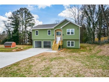 Green house with attached garage and wooden stairs leading to the front entrance at 153 Oak St, Hiram, GA 30141