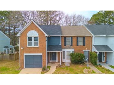 Charming brick townhome with well-maintained lawn and gray garage door offers great curb appeal at 8045 Woodlake Dr, Riverdale, GA 30274