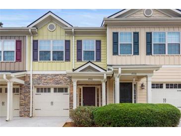 Tan and yellow townhome with stone accents, two-car garage, and landscaping at 4940 Parke Brook Dr, Acworth, GA 30101