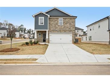 Two-story home with stone and blue siding, a two-car garage, and a well-manicured lawn at 602 Wallace Oak Ln, Lawrenceville, GA 30045