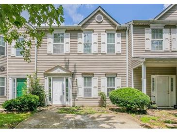 Tan two-story townhouse with green door, landscaping, and driveway at 142 Benfield Cir, Cartersville, GA 30121