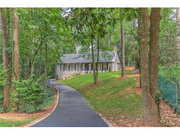 Charming home featuring a stone facade, black shutters, and a long, winding driveway through a lush green landscape at 4540 Club Valley Ne Dr, Atlanta, GA 30319