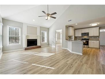 Bright open-concept living room featuring a fireplace, ceiling fan, and hardwood flooring at 20 Trace Ct, Covington, GA 30016