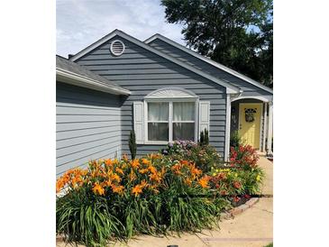 Charming home exterior with blue siding, a yellow front door, and colorful, mature landscaping at 2425 Park Ave, Austell, GA 30106