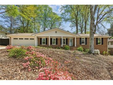 Charming brick home featuring a well-manicured lawn, attached garage, and blooming azaleas in the front yard at 2947 Dunnington Cir, Chamblee, GA 30341