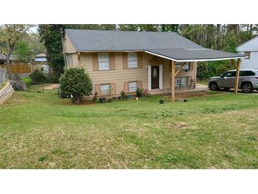 Two-story home with a covered carport, a well-manicured lawn, and mature trees enhancing its curb appeal at 992 Brian Ln, Forest Park, GA 30297