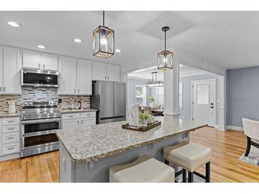 Beautiful kitchen features stainless appliances, granite counters, pendant lighting, and an open floorplan at 641 Virginia Ave, Suwanee, GA 30024