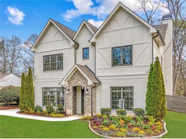 Stunning two-story home featuring a manicured lawn, stone accents, a brick facade, and professional landscaping at 812 Stratford Rd, Avondale Estates, GA 30002