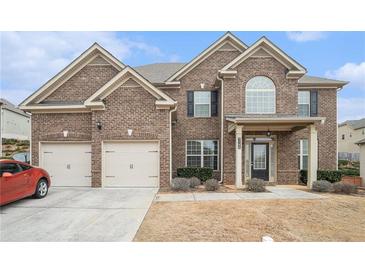 Brick two-story house with three-car garage and manicured lawn at 3780 Casual Ridge Way, Loganville, GA 30052