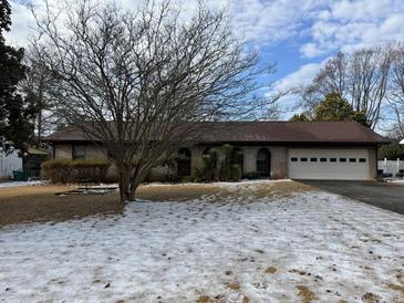 Ranch home with a brown roof, attached garage, and mature tree in front at 457 Castleaire Dr, Stone Mountain, GA 30087