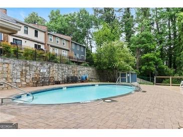 Community in-ground pool surrounded by brick patio, stone wall, seating, and lush trees at 2922 Lavista Way # 2922, Decatur, GA 30033