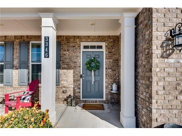 Inviting front porch with brick facade, gray door, and charming wreath at 3346 Long Creek Dr, Buford, GA 30519