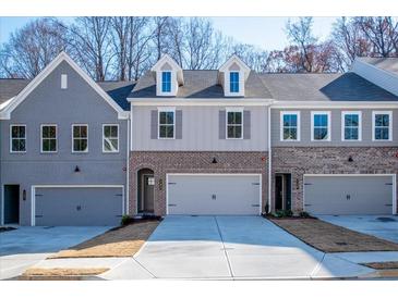 Three-unit townhome building with gray and brick exterior, two-car garages, and landscaping at 143 Bluffington Way, Marietta, GA 30066