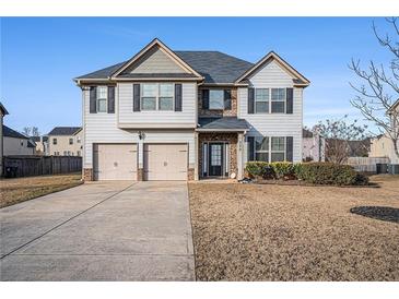 Charming two-story home featuring a two-car garage, complemented by manicured landscaping and a well-maintained front yard at 520 Harmony Way, Locust Grove, GA 30248