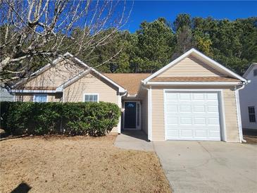 Tan house with a white garage door and well-maintained landscaping at 131 Misty Ridge Trl, Stockbridge, GA 30281