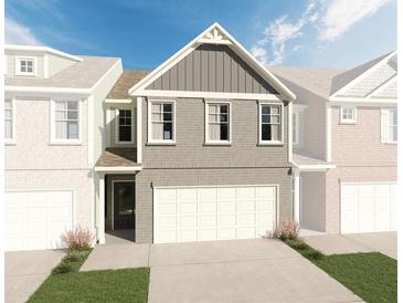3-story townhome with gray brick exterior, 2-car garage, and landscaping at 663 Cygnet Ln, Grayson, GA 30017