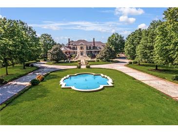 Majestic estate with circular drive and elegant water feature surrounded by lush landscaping at 5200 Moore Rd, Suwanee, GA 30024