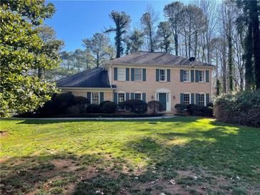 Brick two-story house with green shutters, well-maintained lawn, and mature trees at 11185 Willow Wood Dr, Roswell, GA 30075