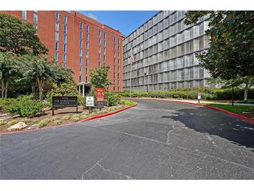 Building exterior of The Habersham Estate, featuring brick and glass architecture, a landscaped area, and a curving driveway at 3060 Pharr Court North Nw # 109, Atlanta, GA 30305