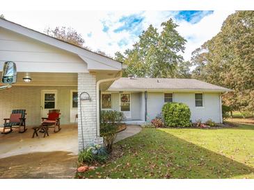 Ranch home with covered porch, rocking chairs, and landscaped yard at 105 Tranquillity Dr, Villa Rica, GA 30180