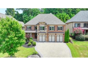 Brick two-story house with three-car garage and landscaped yard at 7890 Royal Melbourne Way, Duluth, GA 30097