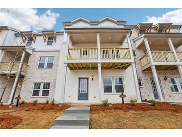 Charming white brick townhome featuring a covered balcony and beautifully landscaped front yard at 4659 Red Lion Pl, Lawrenceville, GA 30044