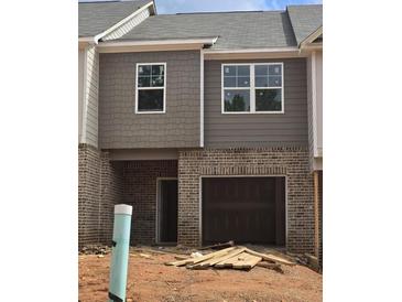 Exterior view of home with gray siding and brick, and attached garage awaiting completion at 2812 Lillian Ln, Douglasville, GA 30135