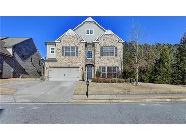 Brick two-story house with a three-car garage and landscaping at 490 La Perla Dr, Sugar Hill, GA 30518