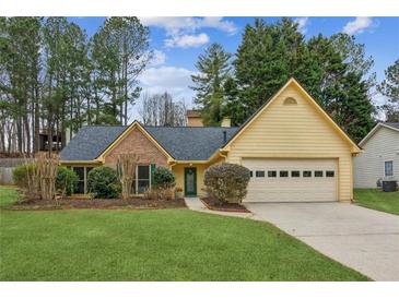 Ranch style home with brick and yellow siding, two car garage, and landscaped lawn at 322 Ravinia Way, Lawrenceville, GA 30044