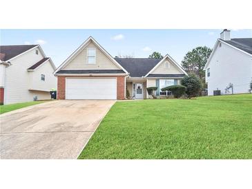 Tan brick house with white garage door and well-manicured lawn at 559 Ransom Way, Stockbridge, GA 30281