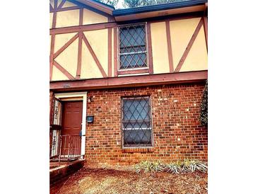 Charming two-story townhouse showcasing brick facade, windows with security bars, and a cozy entrance with an opened security gate at 3278 Abbeywood Dr, Decatur, GA 30034
