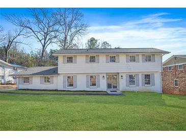 Two story house with white brick exterior, gray shutters, and a large green lawn at 3970 Somerled Trl, Atlanta, GA 30349