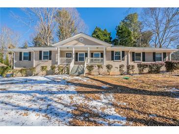 Charming brick home featuring a covered front porch and landscaped front yard at 3002 Arabian Woods Dr, Lithonia, GA 30038