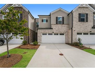 Two-story townhome with brick and siding exterior, two-car garage, and landscaping at 1247 Sunny Lake Dr, Lawrenceville, GA 30043