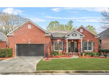 Brick ranch home with attached garage, manicured lawn, and landscaping at 127 Ennisbrook Se Dr, Smyrna, GA 30082