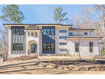 Stunning two-story home with gray and white brick exterior, a stone retaining wall, and landscaping at 4840 Northway Dr, Atlanta, GA 30342