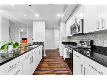 Modern kitchen featuring sleek white cabinets, stainless steel appliances, and dark countertops with breakfast bar at 565 Peachtree Ne St # 804, Atlanta, GA 30308