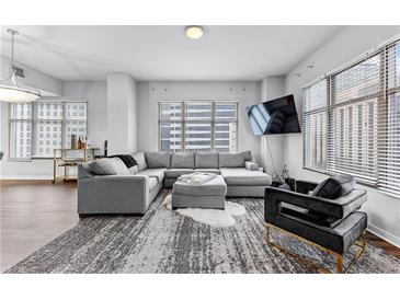 Bright living room features a large sectional sofa, modern decor, and floor-to-ceiling windows at 565 Peachtree Ne St # 804, Atlanta, GA 30308