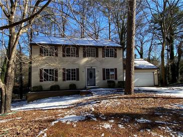Two-story house with brown and beige siding, attached garage, and snowy yard at 5174 Stone Trce, Stone Mountain, GA 30083